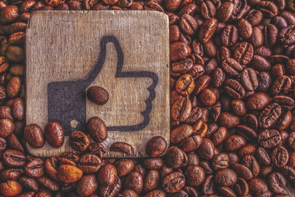 AC移動電源五大好處,,A wooden thumbs up symbol resting on a pile of roasted coffee beans, representing appreciation.